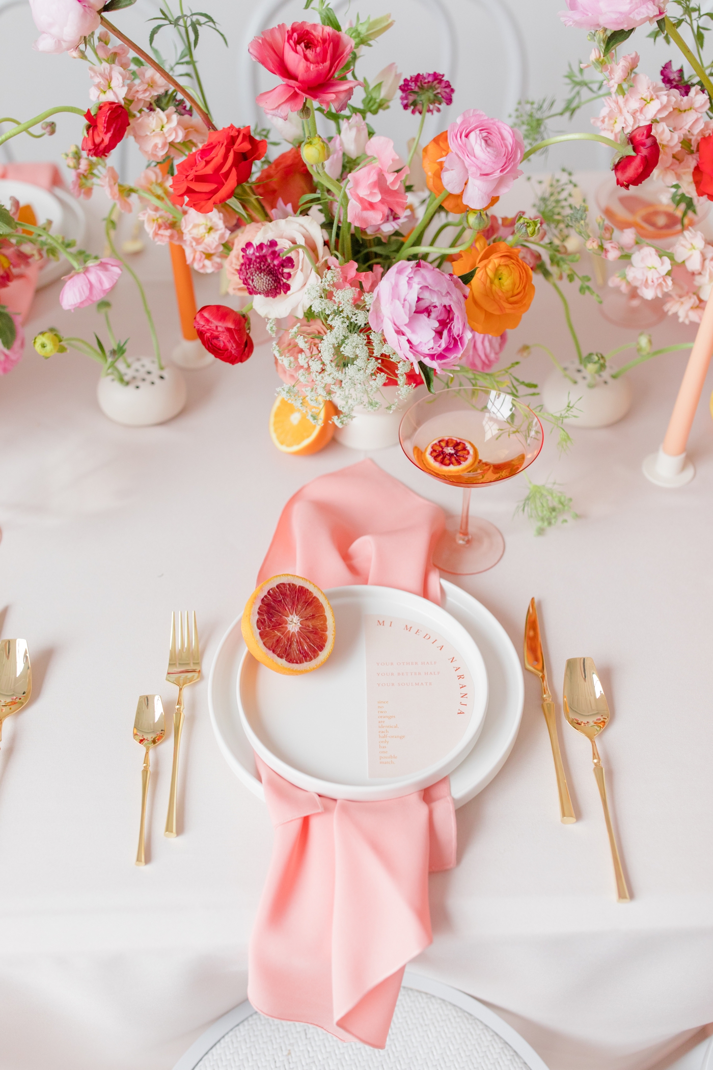 Colorful wedding tablescape with pink linens and citrus fruit accents