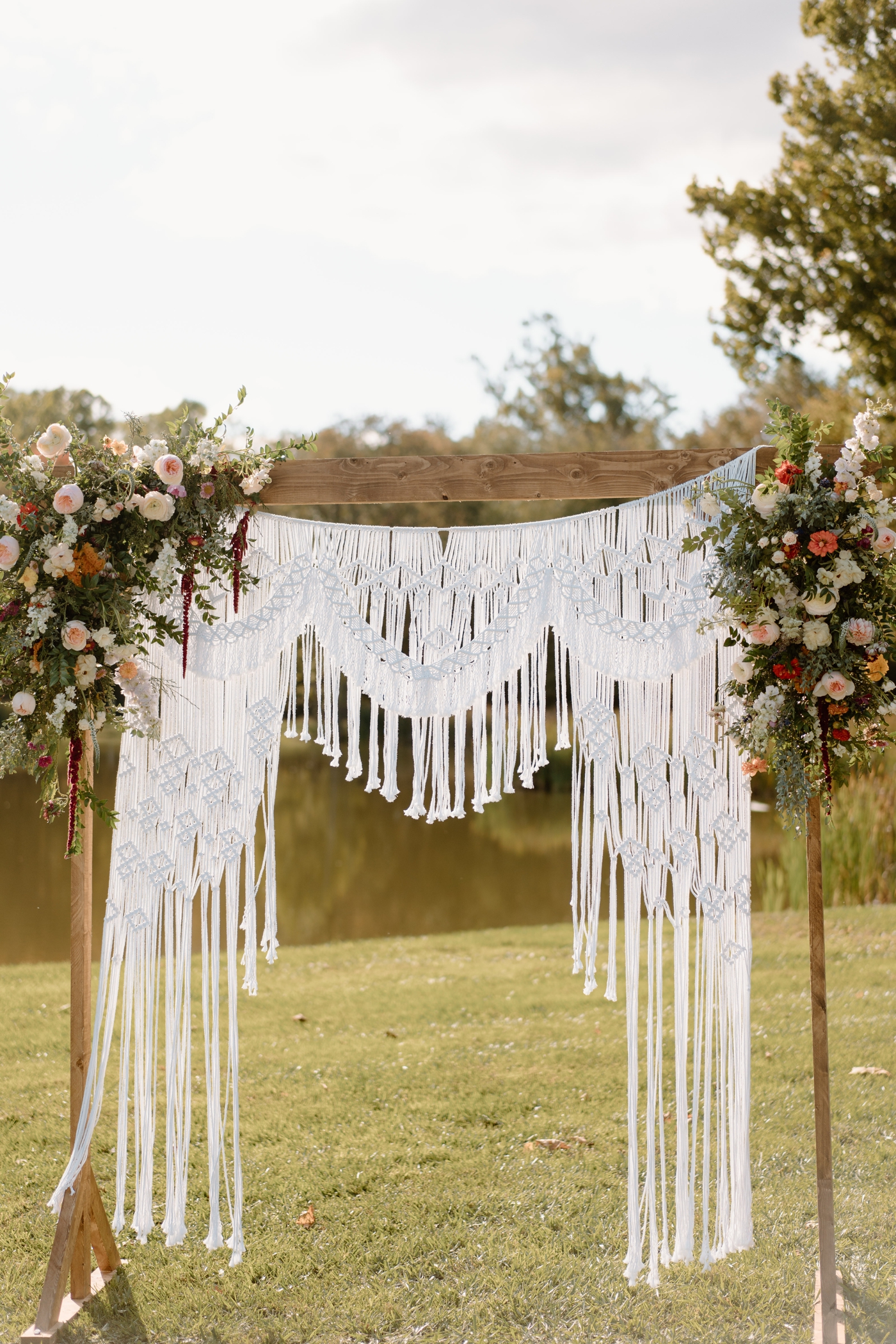 Wooden wedding arch with a macrame backdrop and wildflowers