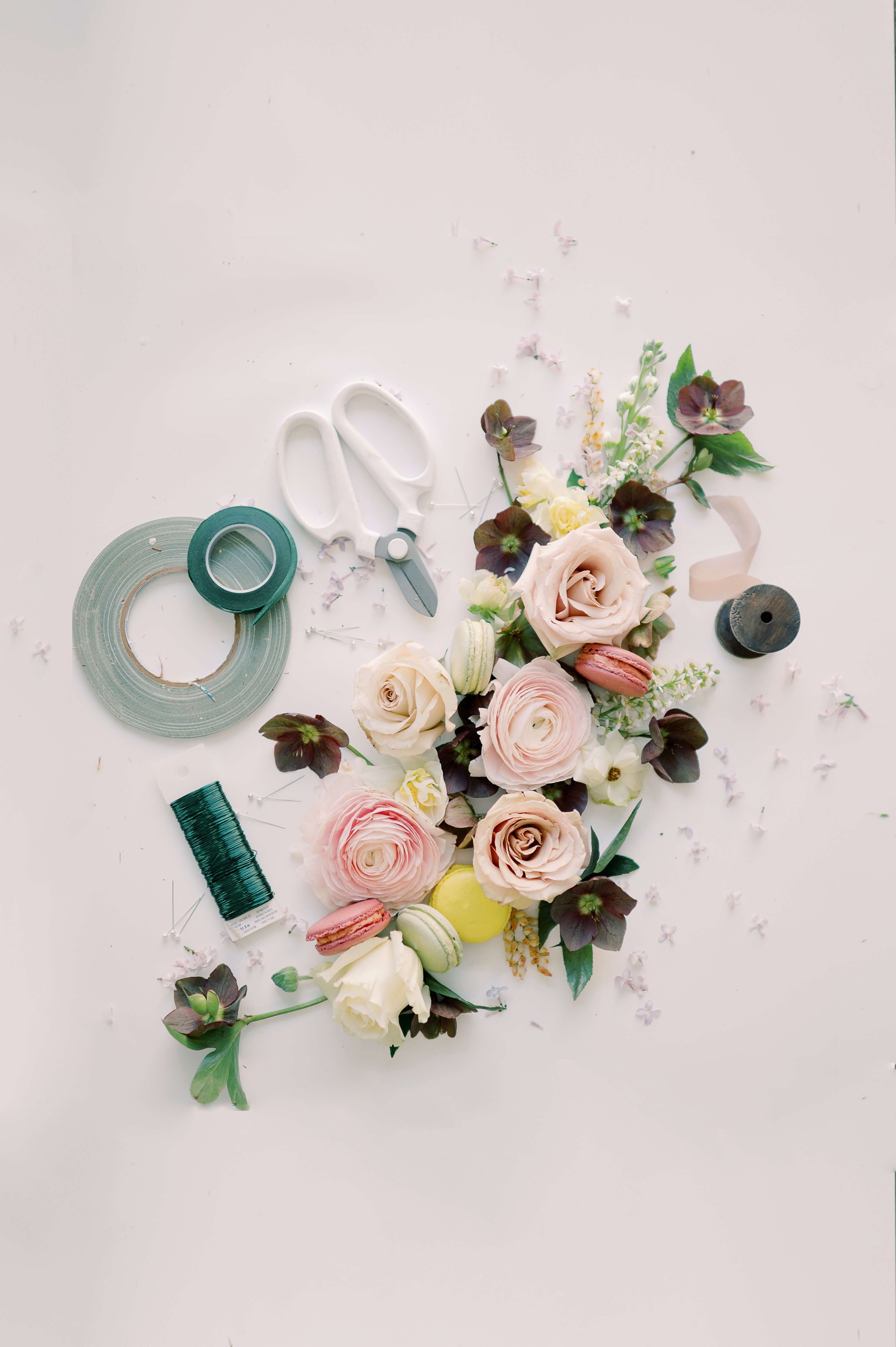 Flatlay photograph of flowers and macarons with florist's shears, ribbon, and twine